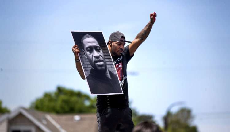 Tony L. Clark holds a photo of George Floyd outside the Cup Food convenience store, Thursday, May 28, 2020, in Minneapolis. Floyd, a handcuffed black man, died Monday in police custody near the convenience story.(Jerry Holt/Star Tribune via AP)