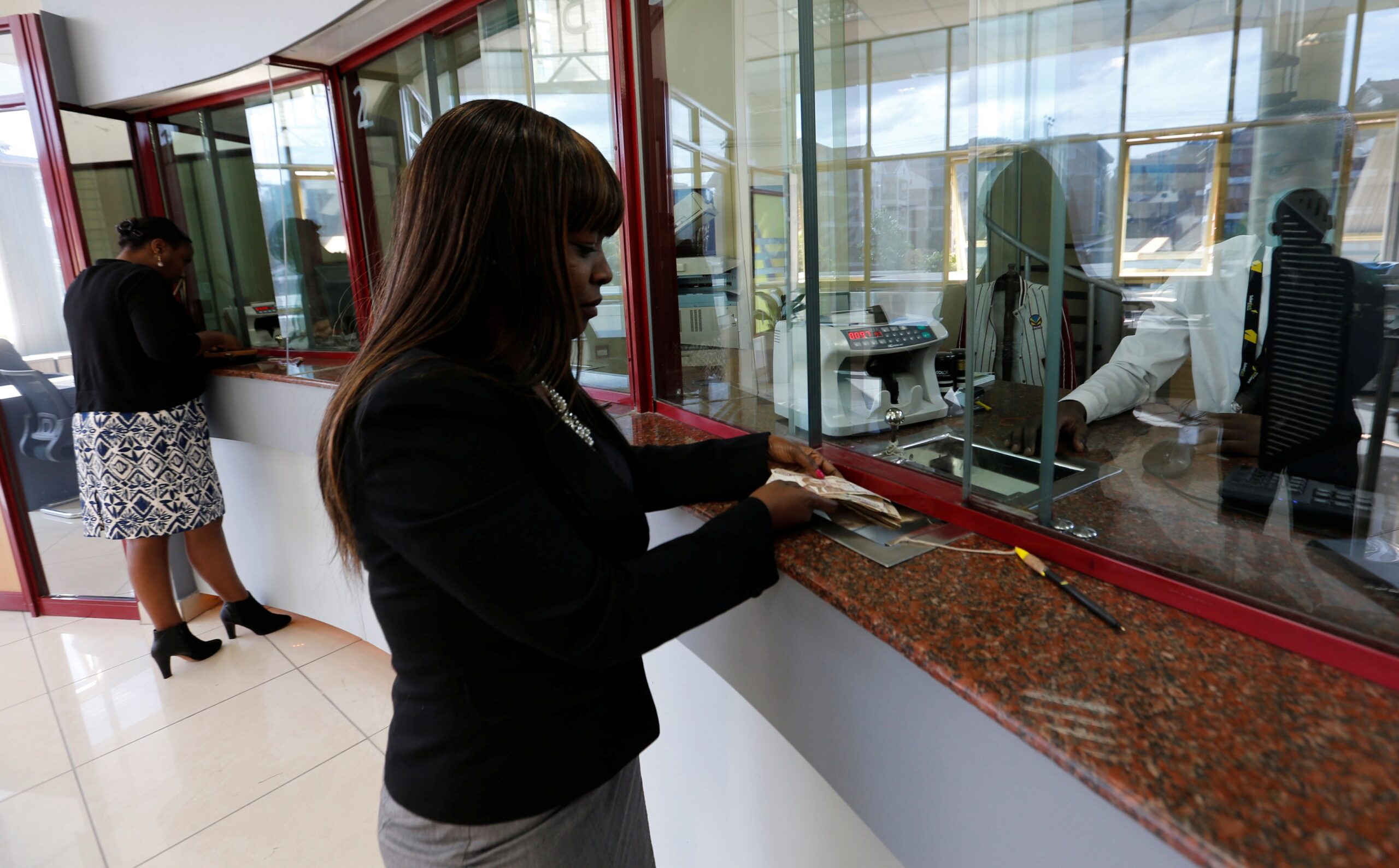 A customer is served at the teller counter inside a banking hall