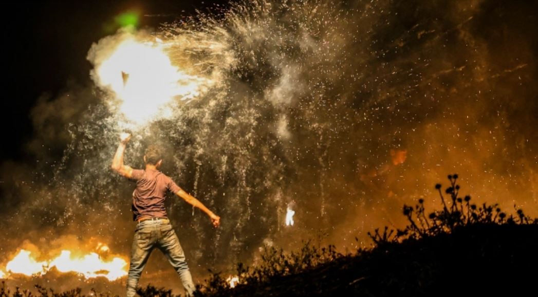 A Palestinian protester throws a burning projectile during a demonstration east of Gaza City near Israel on Tuesday as Israeli ultranationalists marched in Jerusalem’s Old City [Mahmud Hams/AFP]